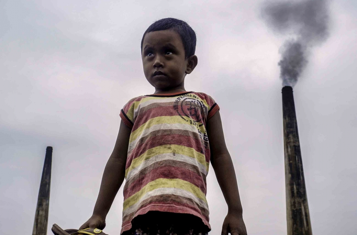 boy in front of smoke stacks