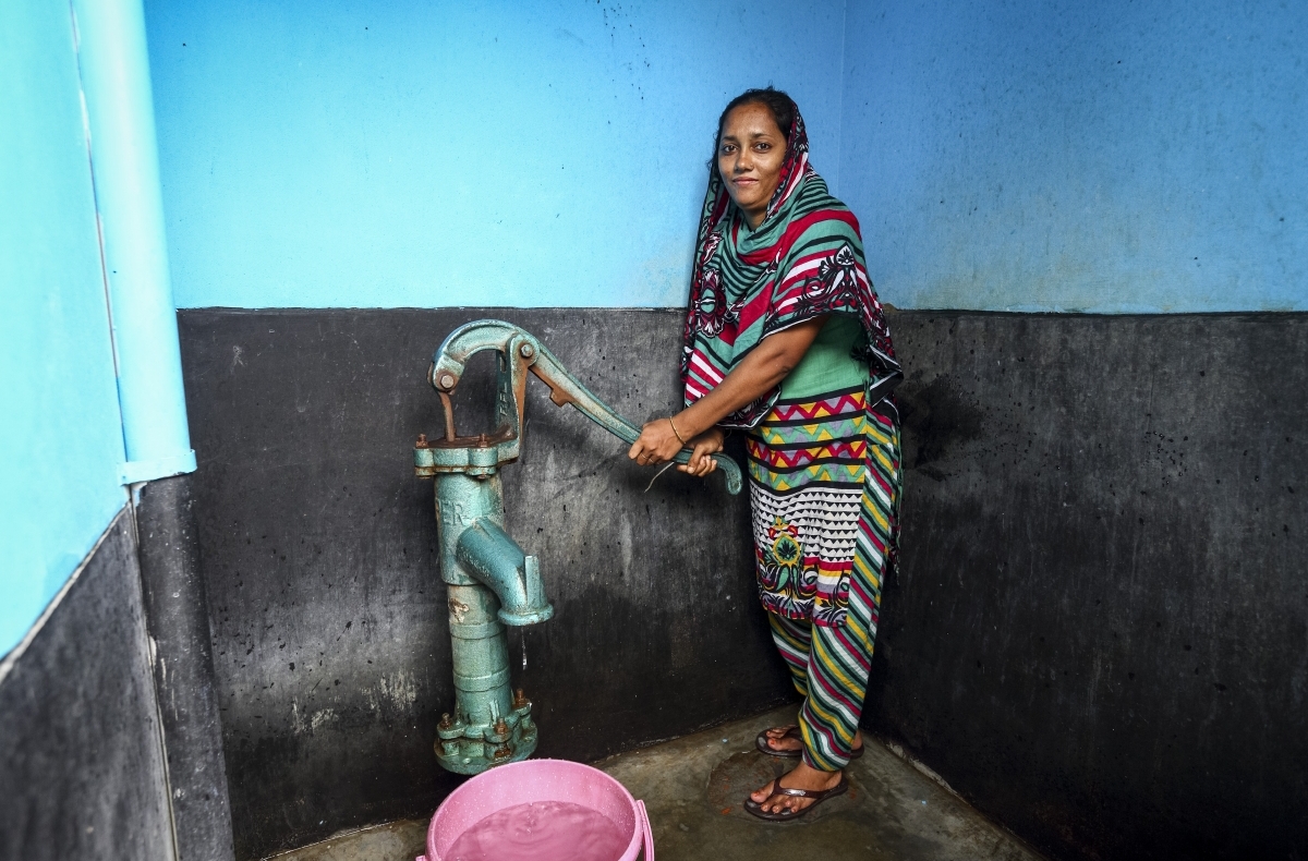 A woman pumps water from a shared community tap