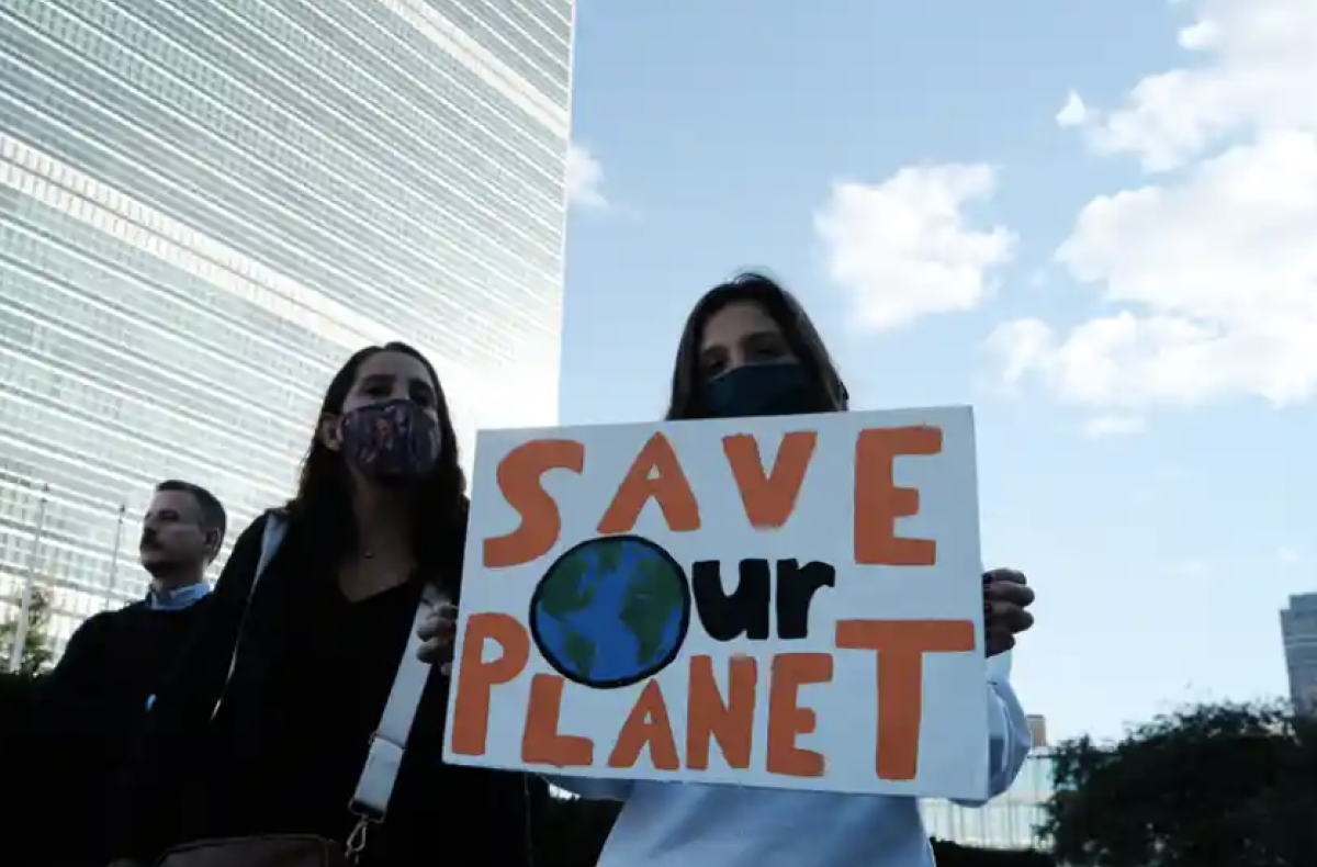A climate protestor holds a sign that says "Save Our Planet"