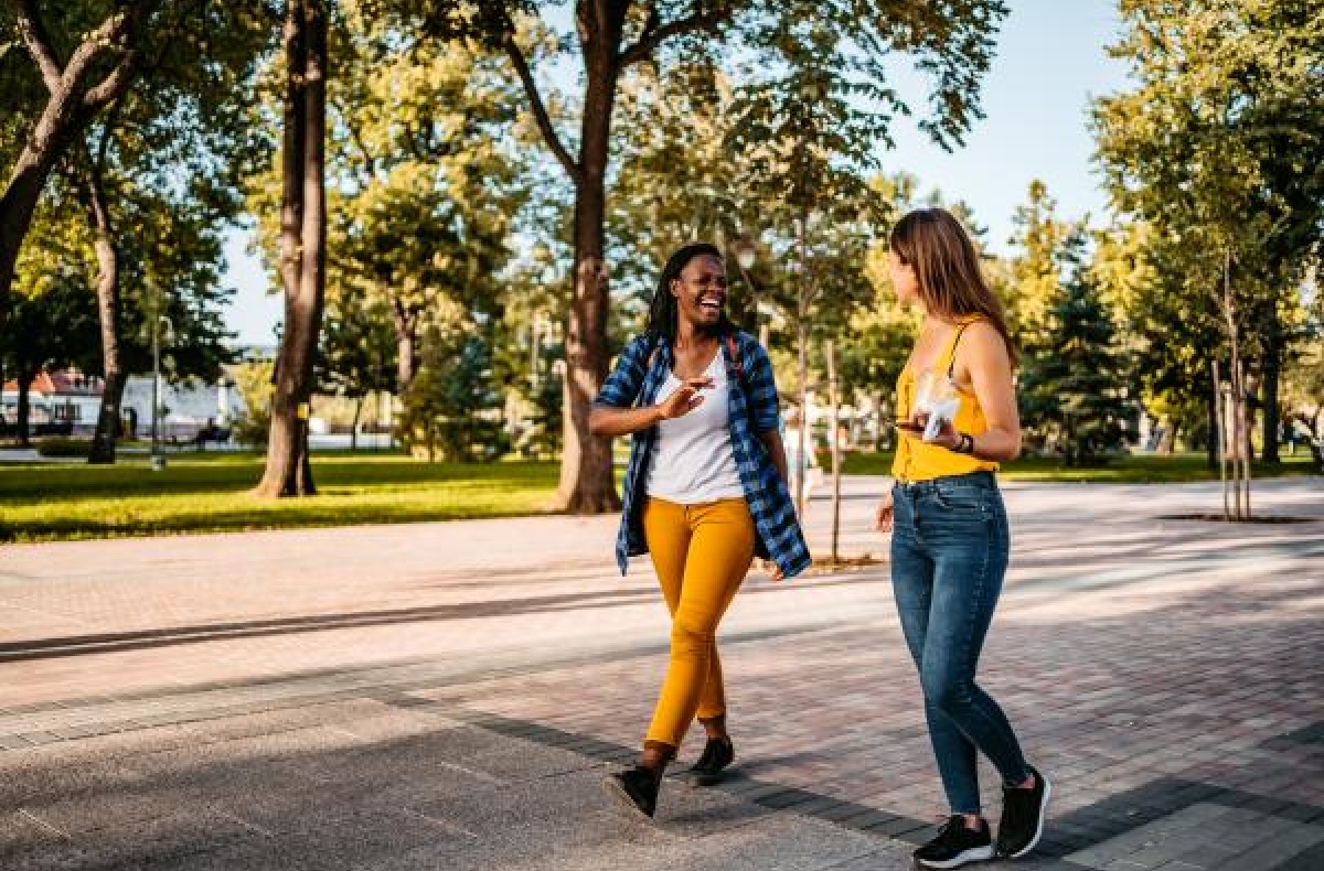 Two women walking down a path surrounded by green spaces