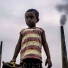 boy in front of smoke stacks