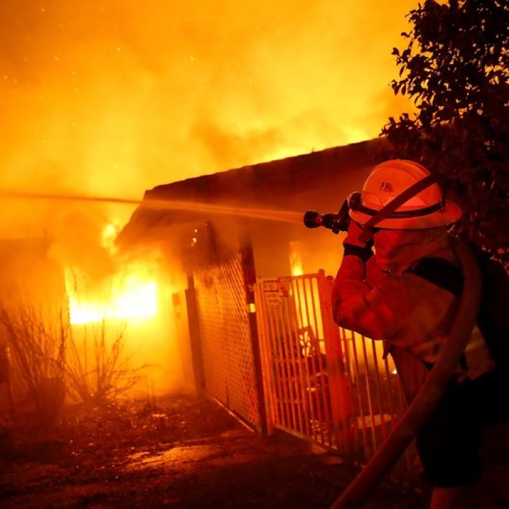 firefighter puts out wildfire burning a house