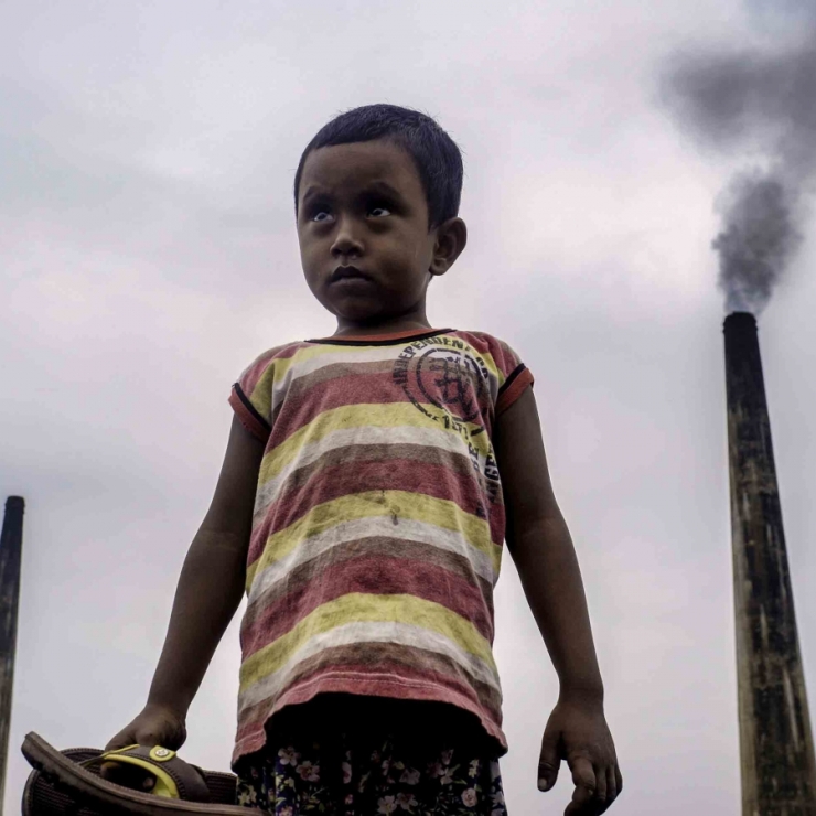 boy in front of smoke stacks