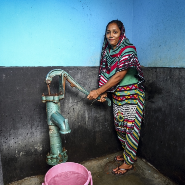 A woman pumps water from a shared community tap