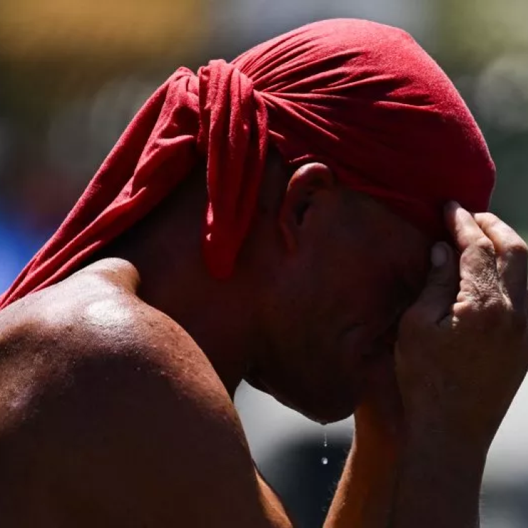 A person covers their head for protection from the sun during a record heat wave in Phoenix, Arizona, on July 18, 2023. The heat wave has spurred debate on if climate change is causing high temperatures.