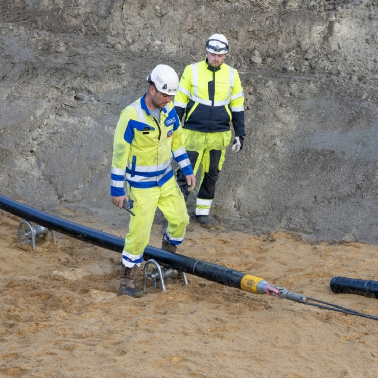 two men work on construction of a high voltage cable connecting Germany and Norway's electricity grids