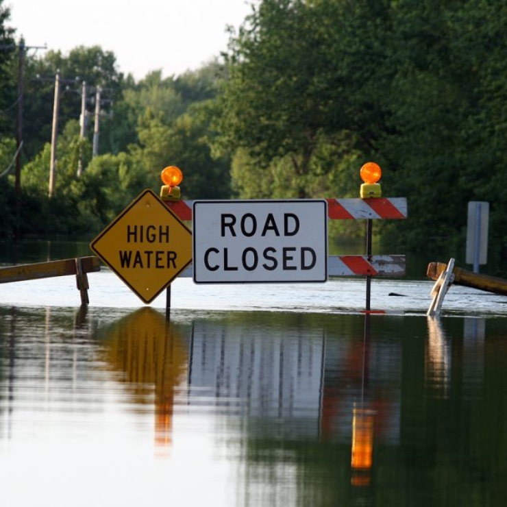 A flooded street with High Water and Road Closed caution signs