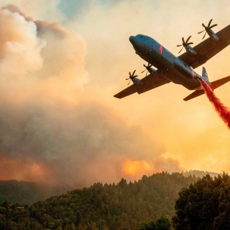 a plane drops fire retardant on a wildfire