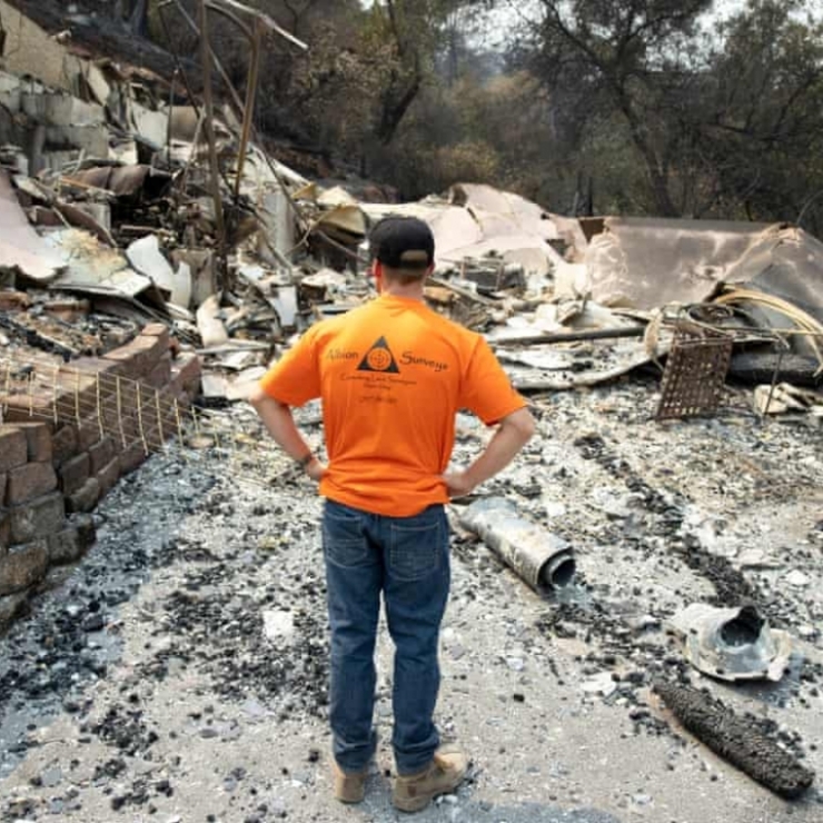 A man surveys the damage after a house was destroyed by wildfire