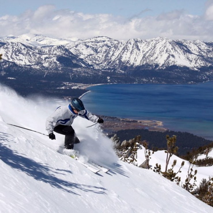 a person skiing down a hill with a snowy lake in the background