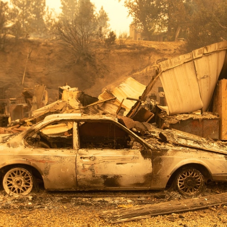 A burned car and house remains after a wildfire