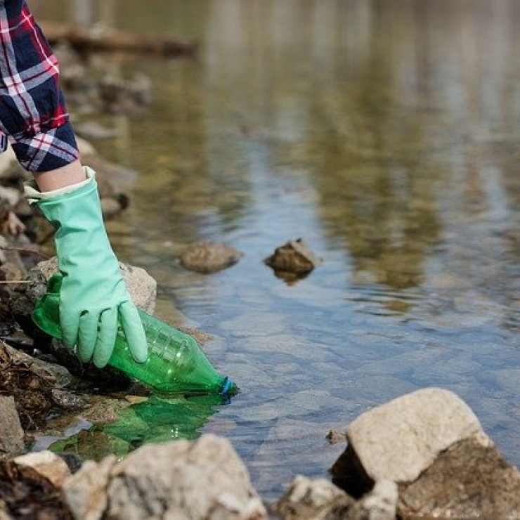 Person removing plastic waste from stream.