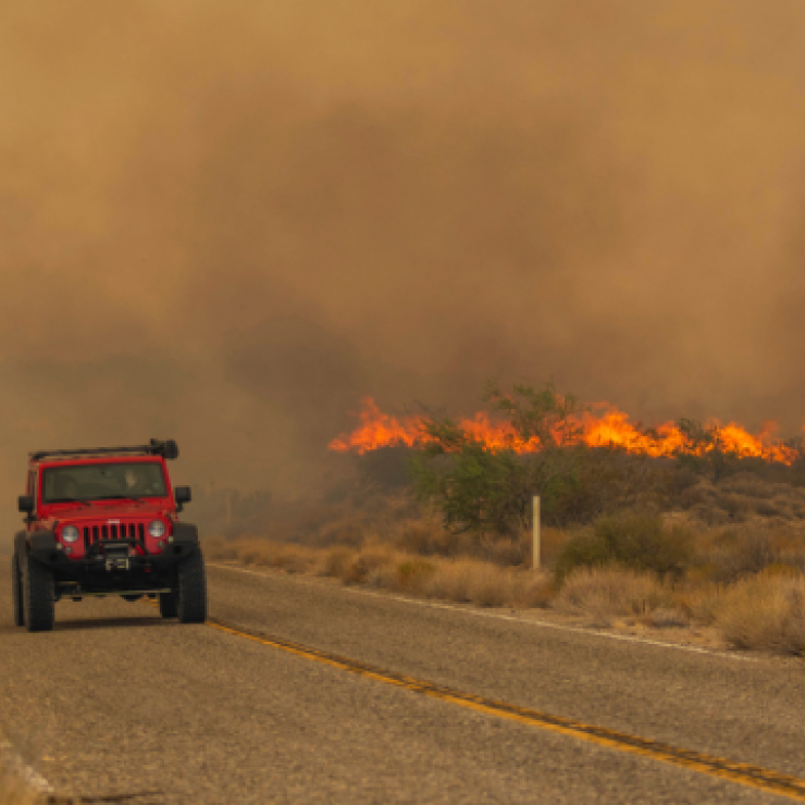 A car passes rising flames from the York Fire on Ivanpah Rd., on July 30 in the Mojave National Preserve, Calif. Crews battled “fire whirls” in California’s Mojave National Preserve this weekend as a massive wildfire crossed into Nevada amid dangerously high temperatures and raging winds.