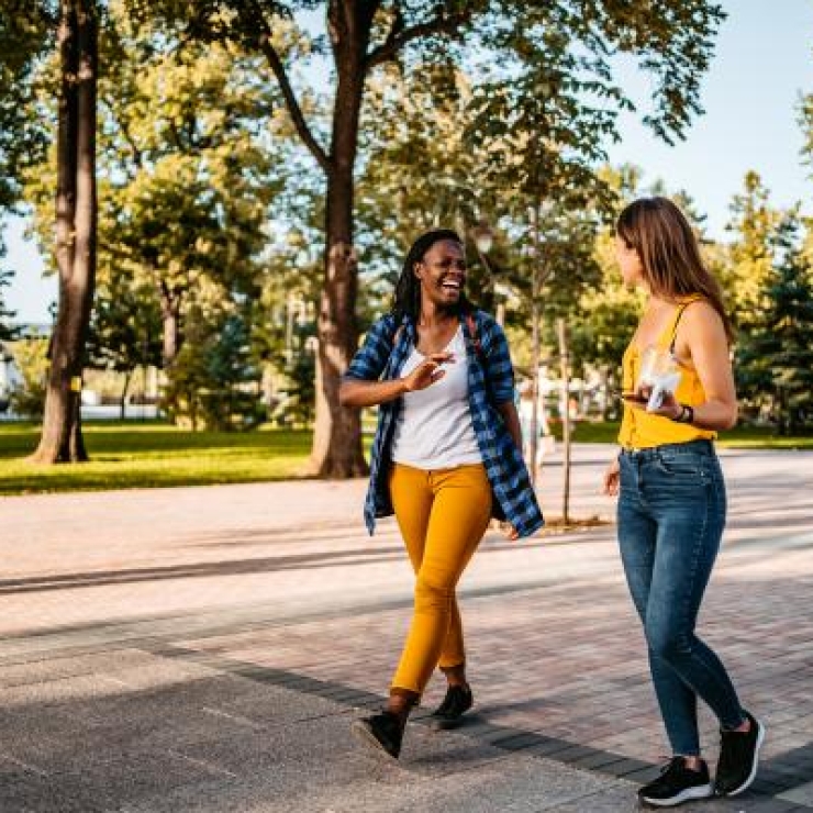 Two women walking down a path surrounded by green spaces